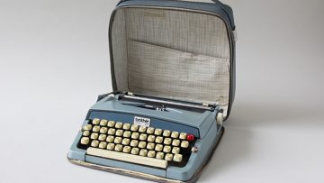 A blue typewriter in an opened blue leather case