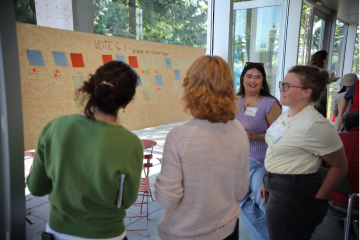 Four adults surround a post-it note feedback poster.